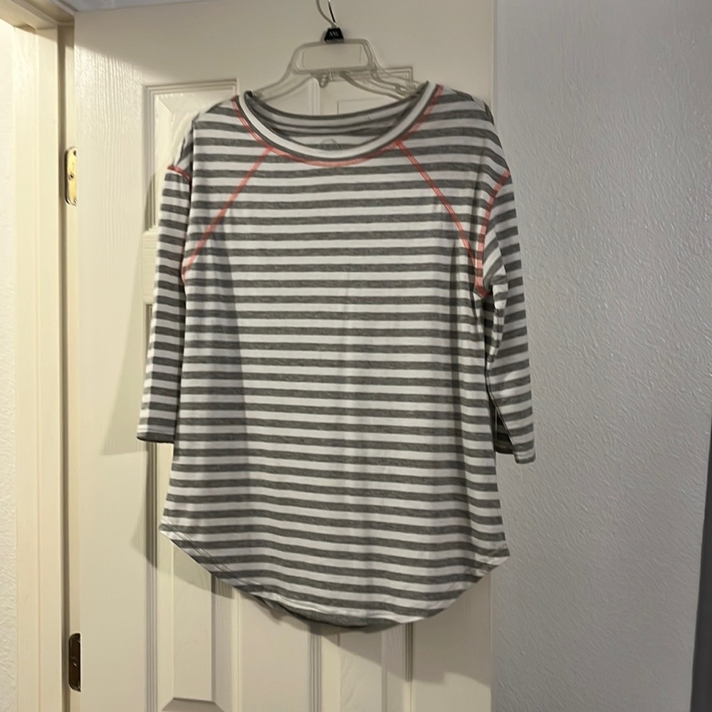 Maurice’s small shirt with gray and white stripes has pink on the top.